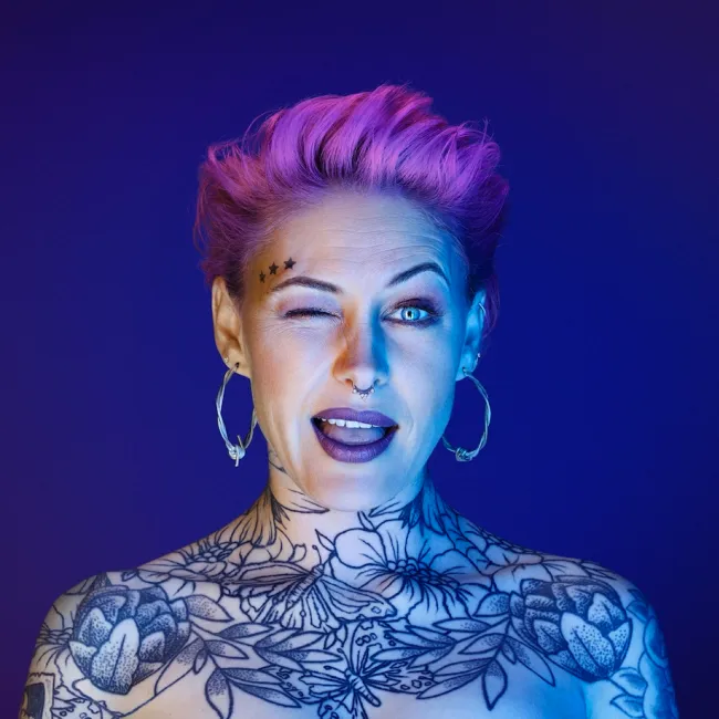 A woman covered in tattoos and winking