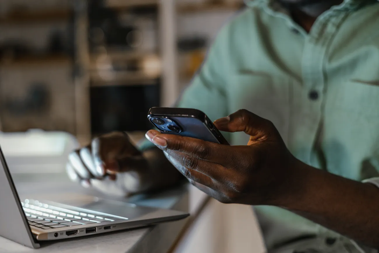 Hands using a phone and laptop computer