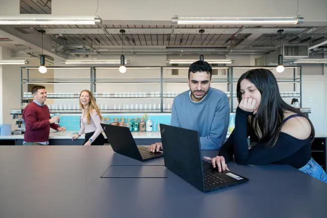 People in the kitchen area of an office building, laughing