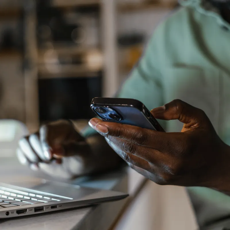 Hands using a phone and laptop computer